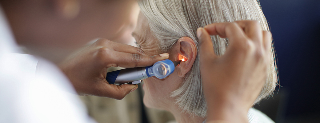 Close-up of hearing care professional shining a light in senior woman's ear